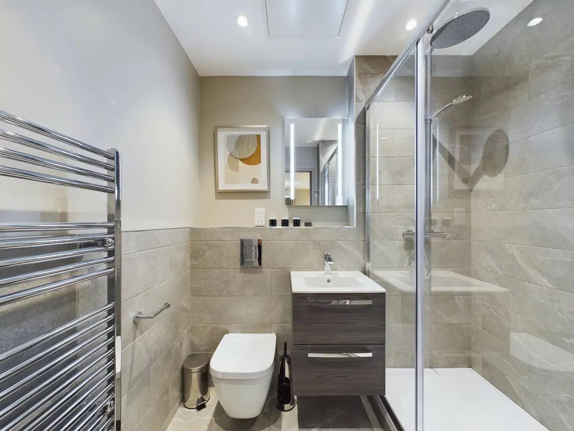 A modern bathroom with a glass shower enclosure, a toilet, a sink, and a vanity with a mirror.