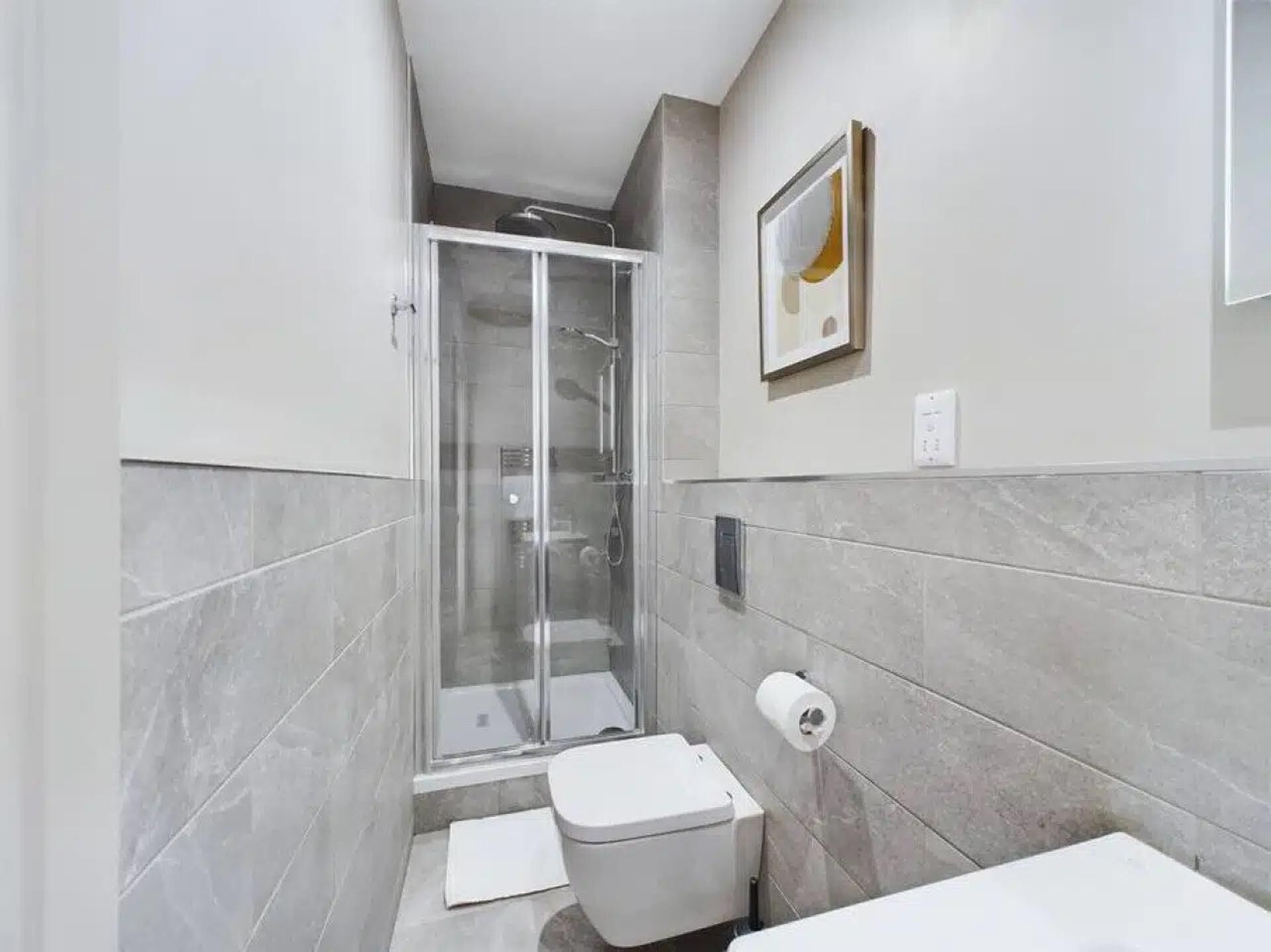 Un baño con ducha de vidrio, inodoro y lavamanos.