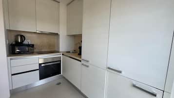 A compact kitchen with a microwave, oven, and sink.