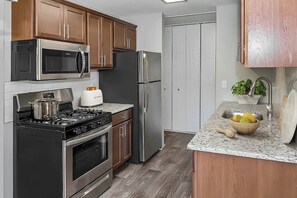 A kitchen with stainless steel appliances, wooden cabinets, a granite countertop, and a built-in oven. - Cozy MSP 1BR Retreat: Pets OK, Pool & Gym-159/nt, 4499/mn{Negotiable} (Minneapolis)