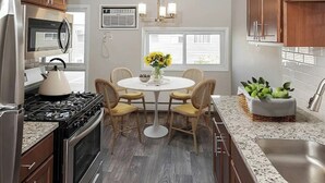 A kitchen with a round dining table, wooden chairs, a refrigerator, stove, and a sink. - Cozy MSP 1BR Retreat: Pets OK, Pool & Gym-159/nt, 4499/mn{Negotiable} (Minneapolis)