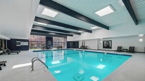 A large indoor swimming pool with clear water, surrounded by lounge chairs and a ceiling with skylights. - Cozy MSP 1BR Retreat: Pets OK, Pool & Gym-159/nt, 4499/mn{Negotiable} (Minneapolis)
