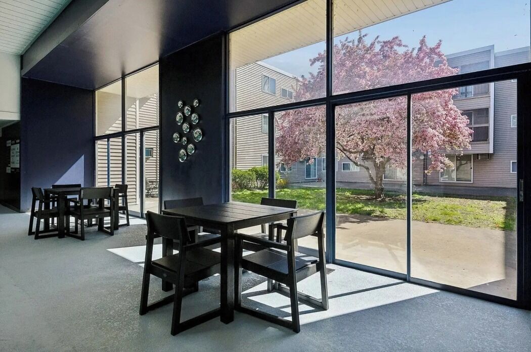 Ein modernes Interieur mit Essbereich, großen Fenstern und Blick auf ein Gebäude mit Kirschblüten.