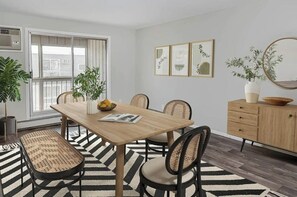 Ein Essbereich mit einem Holztisch, vier Stühlen, einer Bank, einem Buffet und einem Blumentopf.