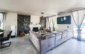 A modern living room with a stone wall, a fireplace, a large sofa, and a flat-screen TV mounted on the wall. - EL ARENAL - CALA ESTANCIA N6 (Mallorca)