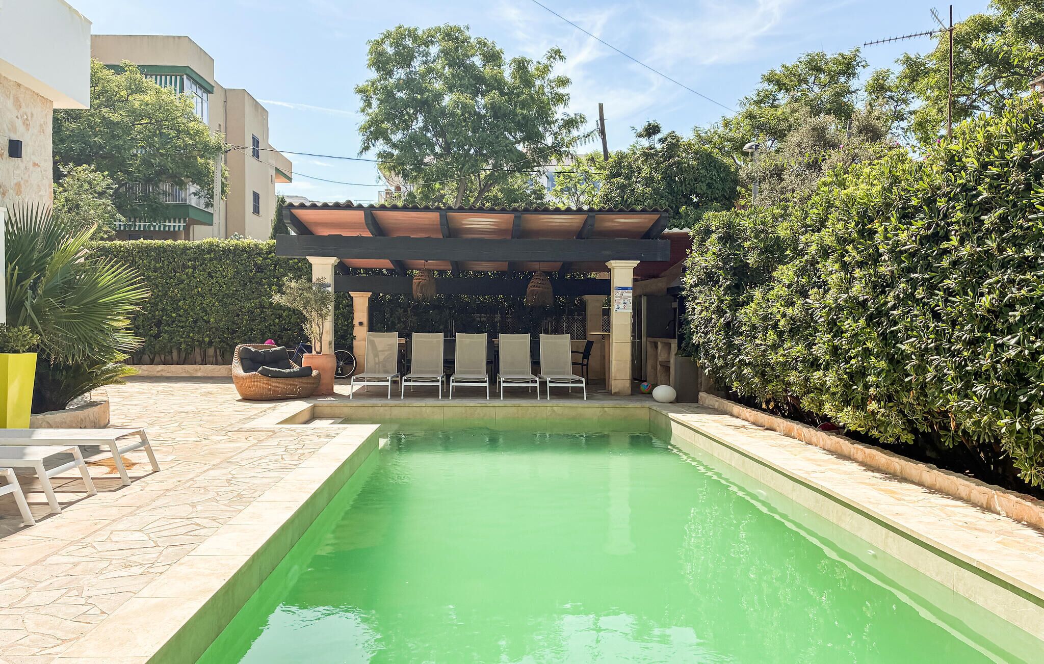 Une piscine agrémentée d’une pergola, de chaises longues et d’une terrasse carrelée.