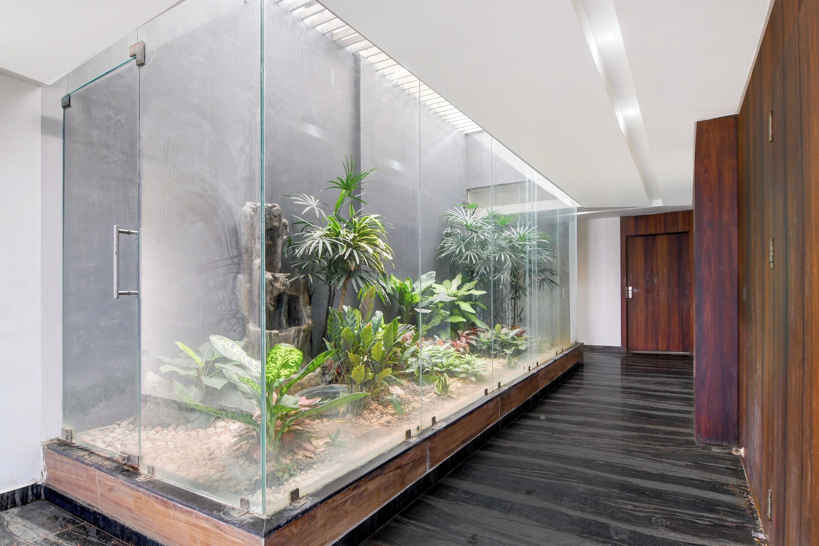 Um corredor com um terrário de vidro contendo diversas plantas e um pequeno elemento aquático.