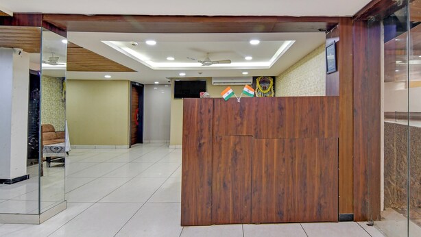 A reception area with a wooden reception desk, a sofa, and a television. - Collection O Infocity Square Bhubaneswar (Bhubaneshwar)