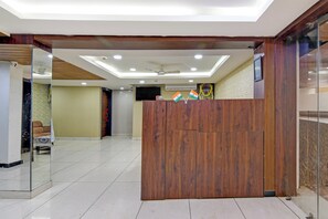 Un espace d’accueil comprenant un comptoir de réception en bois, un canapé et un téléviseur.