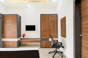 A bedroom with a bed, a desk, a chair, and wardrobe units.