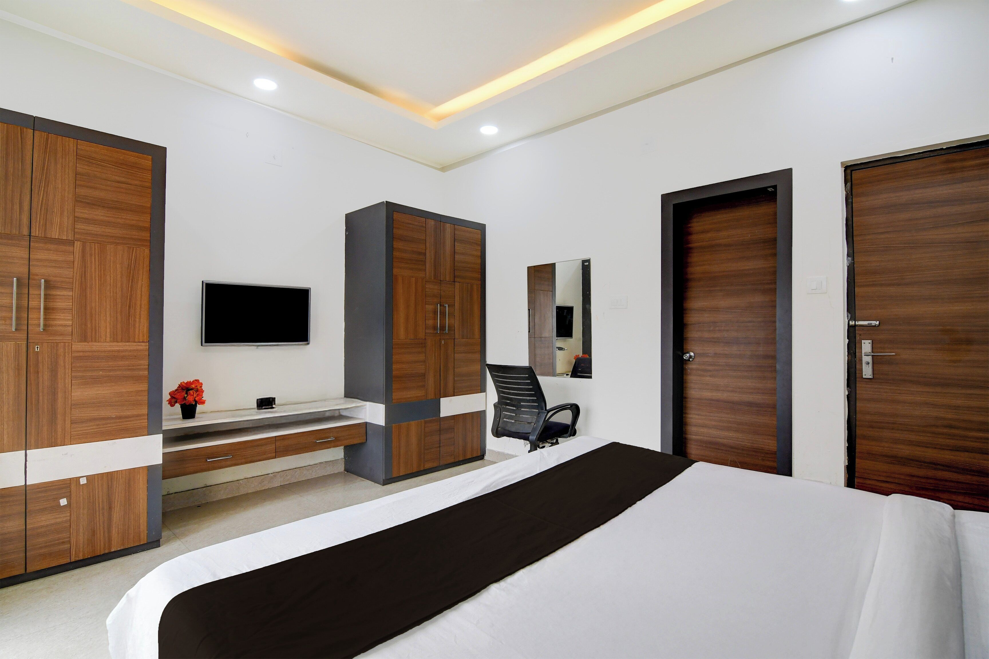 Un dormitorio moderno con cama, televisor, escritorio y armarios.
