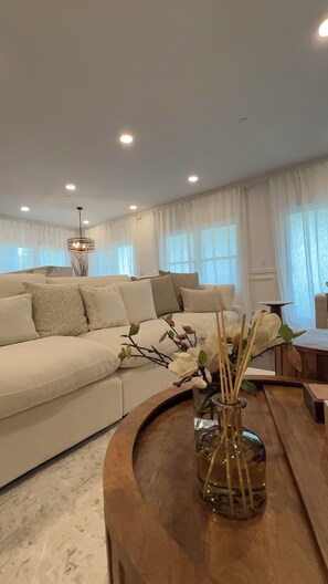Ein modernes Wohnzimmer mit einer Couch, einem Holztisch mit einer Vase und einer Chandelier.