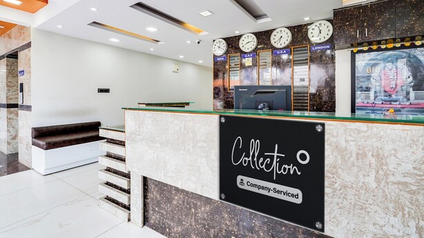 Un comptoir d’accueil avec des horloges indiquant différents fuseaux horaires, un panneau indiquant « Collection et service après-vente », et un escalier menant à un étage supérieur.