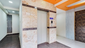 Un couloir avec un mur de marbre, une porte et un panneau indiquant le deuxième étage.