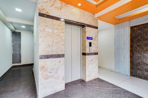 Un couloir avec un mur de marbre, une porte et un panneau indiquant le deuxième étage.