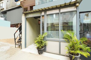 A building with a large window, a staircase, and two potted plants.