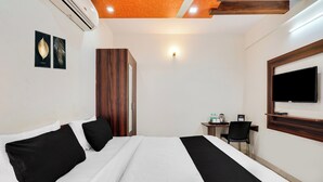 Une chambre d’hôtel comprenant un lit, un bureau, une chaise, une télévision et une armoire.
