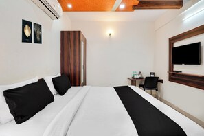 Une chambre d’hôtel comprenant un lit, un bureau, une chaise, une télévision et une armoire.