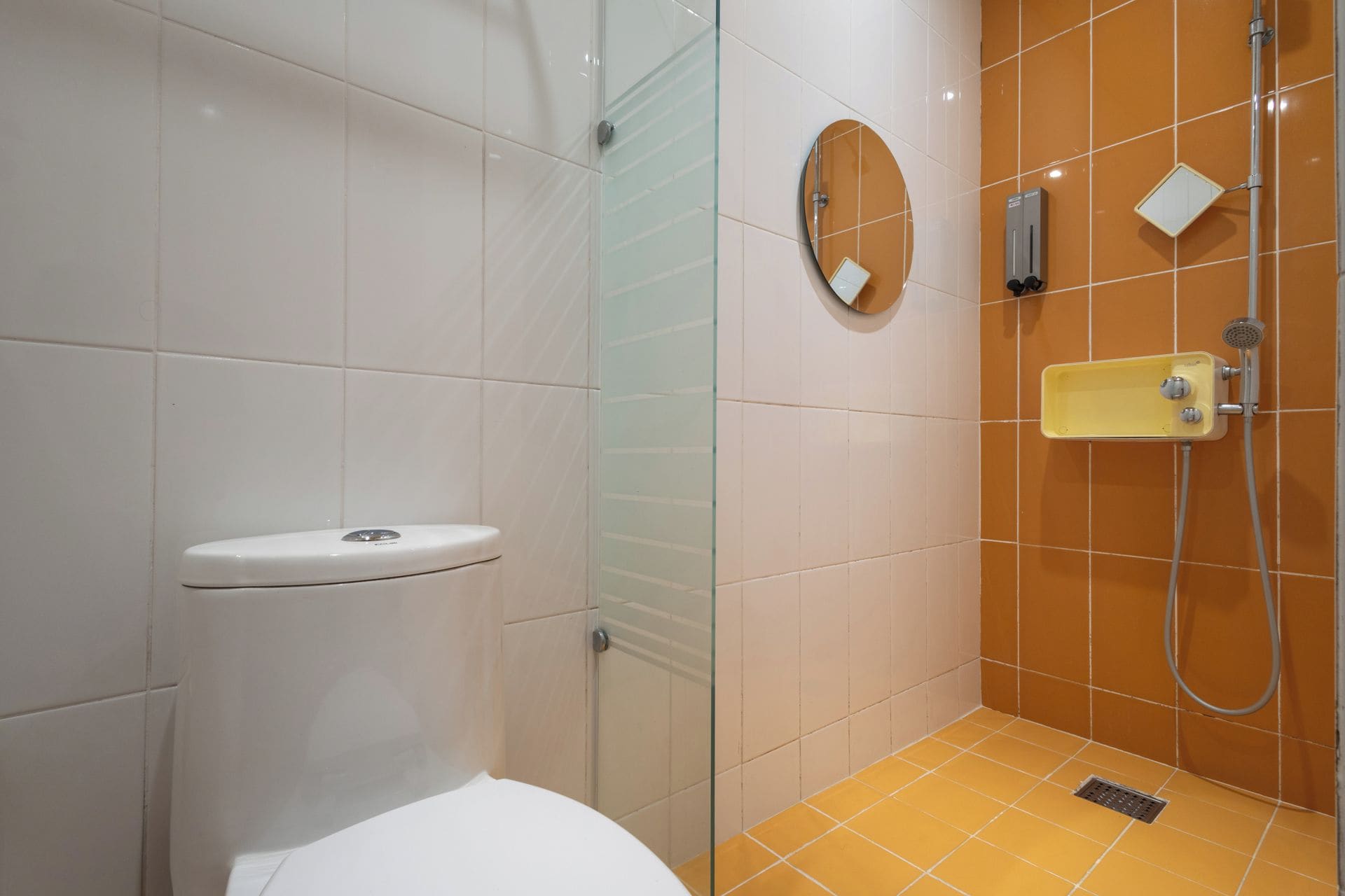 A bathroom with a toilet, a glass shower enclosure, and a sink with a mirror.