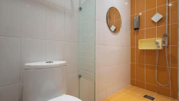 A bathroom with a toilet, a glass shower enclosure, and a sink with a mirror.