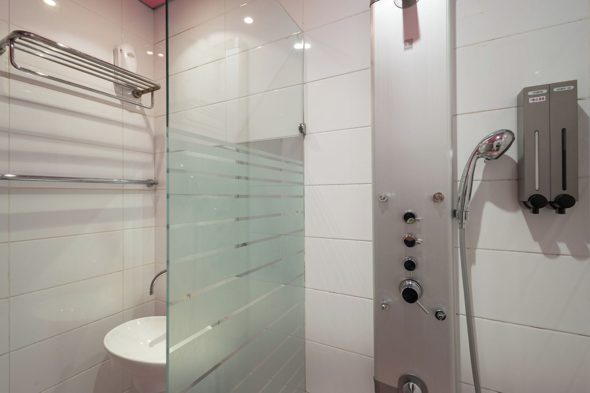 A modern bathroom with a glass-enclosed shower, a white sink, and a towel rack.
