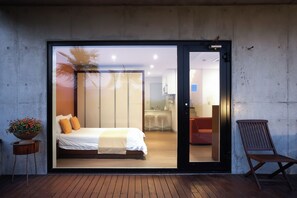 A modern bedroom with a large sliding glass door leading to a bathroom and a kitchen area. - Tropical Dream Resort (Geoje)