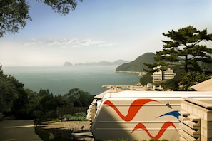 A coastal view with a clear sky, a body of water, and a mountainous landscape in the distance. - Tropical Dream Resort (Geoje)