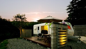 Una caravana compacta para exteriores con un espacio tipo terraza, una parrilla y una mesa.