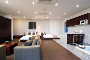 A modern hotel room with a bed, a sofa, a kitchenette, and a bathroom. - Tropical Dream Resort (Geoje)