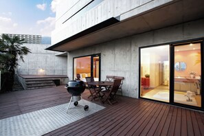 Eine Terrasse im Freien mit Grill, Esstisch und Stühlen.