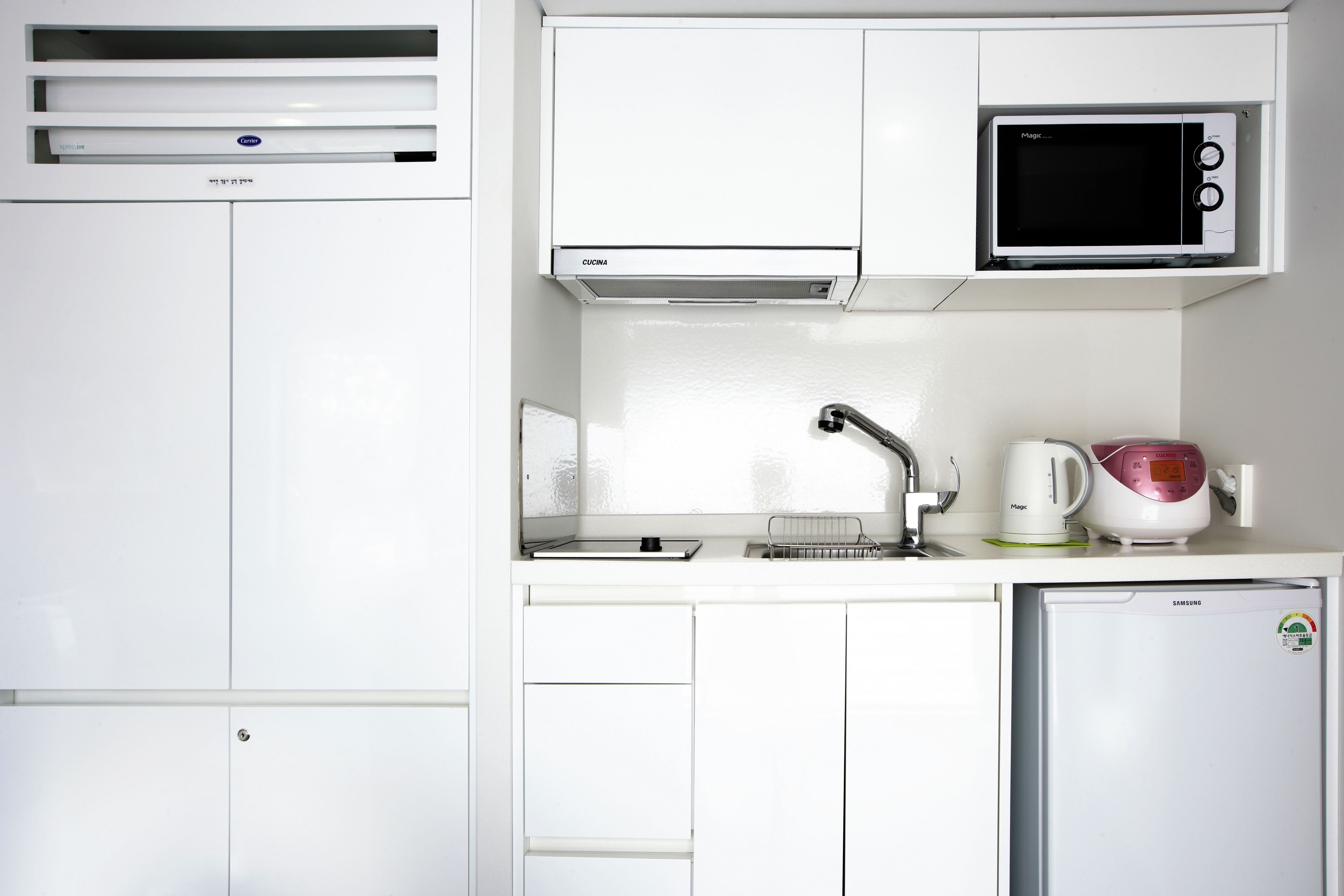 A compact kitchenette with a microwave, a small refrigerator, and a sink.