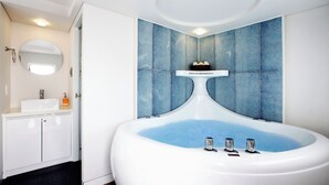 Un baño con una bañera independiente, un espejo, un lavamanos y baldosas de pared estampadas.