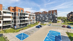 Ein moderner Apartmentkomplex mit mehreren Gebäuden, einem Parkplatz und ausgewiesenen Behindertenparkplätzen.