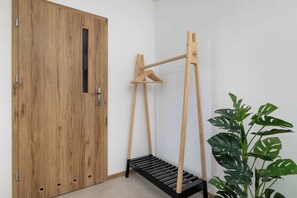 Una puerta de madera con un ventanal pequeño, un tendedero de madera y una planta en maceta.