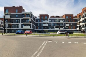 Un edificio residencial moderno de varios pisos con un área de estacionamiento al frente.