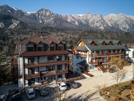 A hotel with multiple floors, balconies, and a parking area with cars.