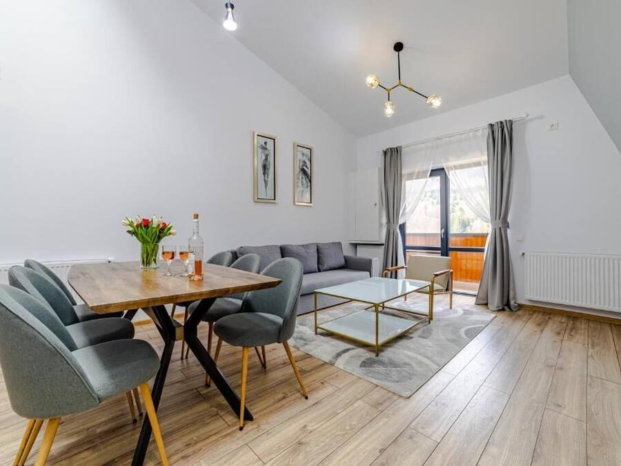 Una sala de estar moderna con comedor, un juego de sofás y un ventanal con cortinas.