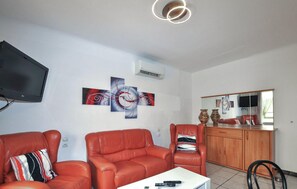 A living room with red leather chairs, a flat-screen TV, abstract wall art, and a wooden cabinet. - 2 bedroom gorgeous apartment in Amélie-les-Bains (Amélie-les-Bains)