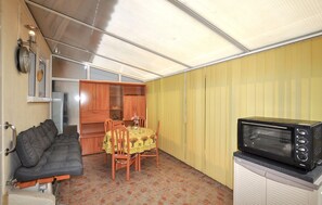Ein kompakter Wohnbereich mit Esstisch, Stühlen, einer Couch, einer Mikrowelle und einem Schrank.
