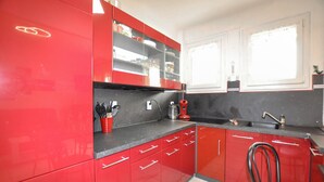 Una cucina con mobili rossi, un piano di lavoro nero e una macchina da caffè.