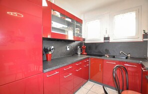 Eine Küche mit roten Schränken, einer schwarzen Arbeitsplatte und einer Kaffeemaschine.