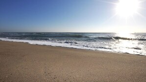 Una spiaggia con onde, cielo sereno e sole splendente.