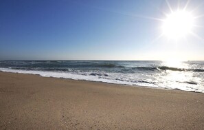 Ein Strand mit Wellen, blauem Himmel und strahlender Sonne.
