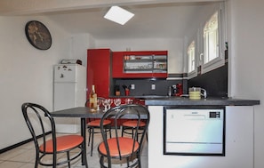 A compact kitchen with a refrigerator, a coffee machine, and a dining area with chairs and a table. - 2 bedroom gorgeous apartment in Amélie-les-Bains (Amélie-les-Bains)
