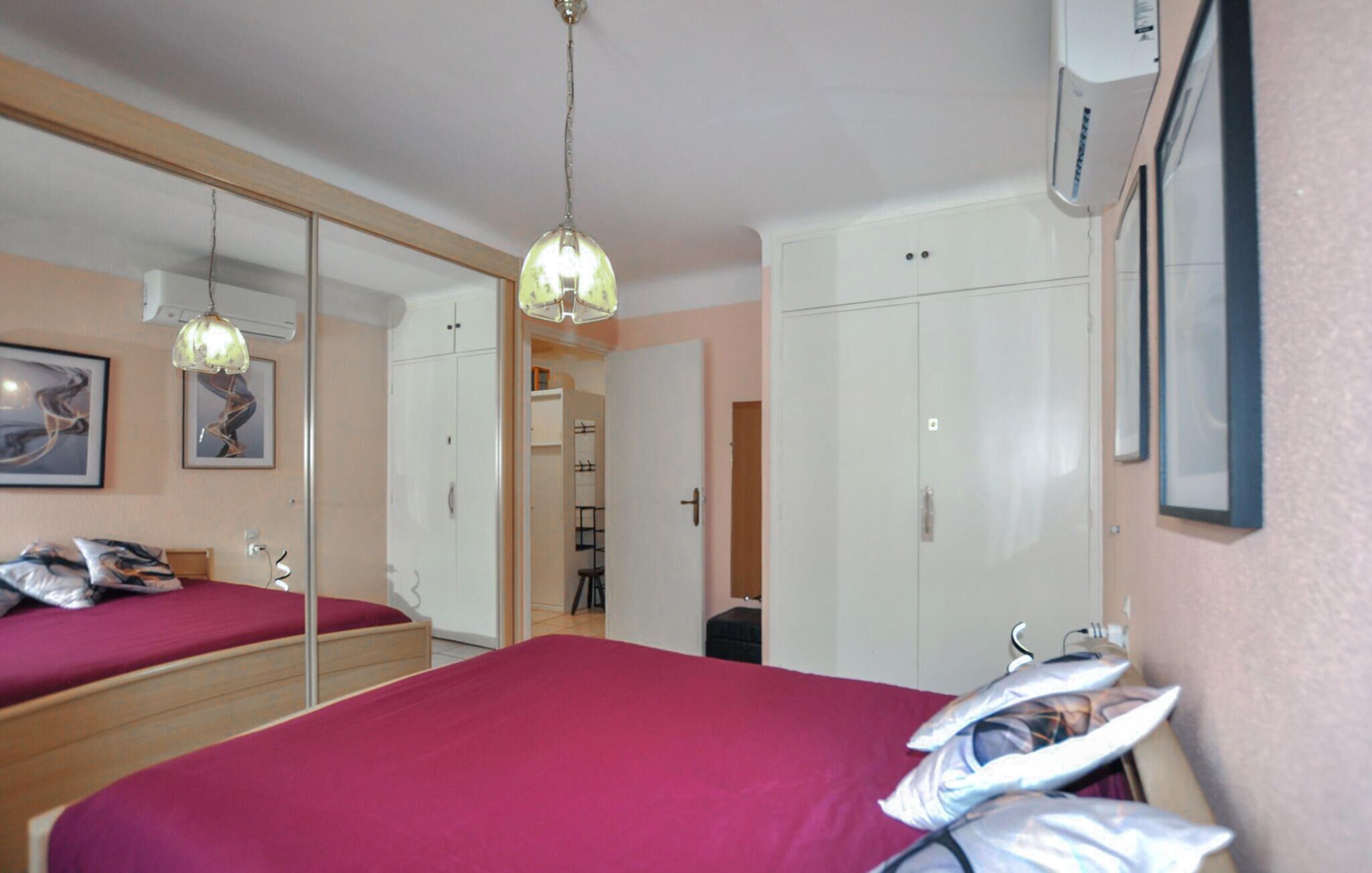 Ein Schlafzimmer mit einem großen Spiegel, einem Bett mit roter Bettdecke und einem Kleiderschrank.