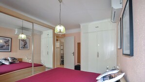 Una camera da letto con un grande specchio, un letto con copripiumino rosso e un armadio.