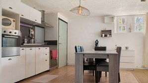 A modern kitchen with built-in appliances, a dining area with a table and chairs, and a hanging light fixture. - Apartment 'Villa Andalouse' with Private Terrace, Wi-Fi and Air Conditioning (Poussan)
