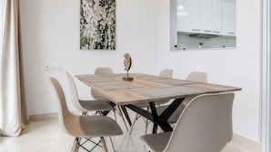 A modern dining area with a wooden table, four chairs, and pendant lighting. - Phos Residence by Rentals Pro - Neos Marmaras Halkidiki (Neos Marmaras)