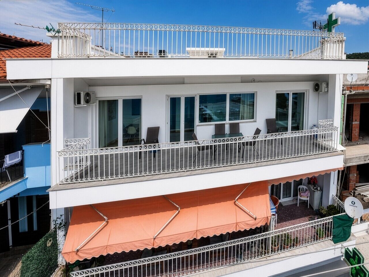 A two-story building with balconies, outdoor seating, and a satellite dish.