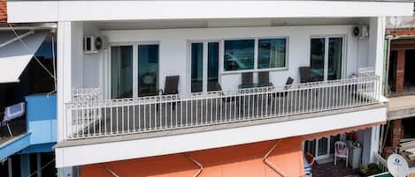 Un edificio de dos pisos con balcones, asientos exteriores y una antena parabólica.